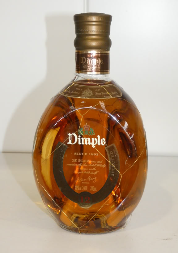 A bottle of Dimple whisky with a gold cap and a label on the front, set against a plain background.