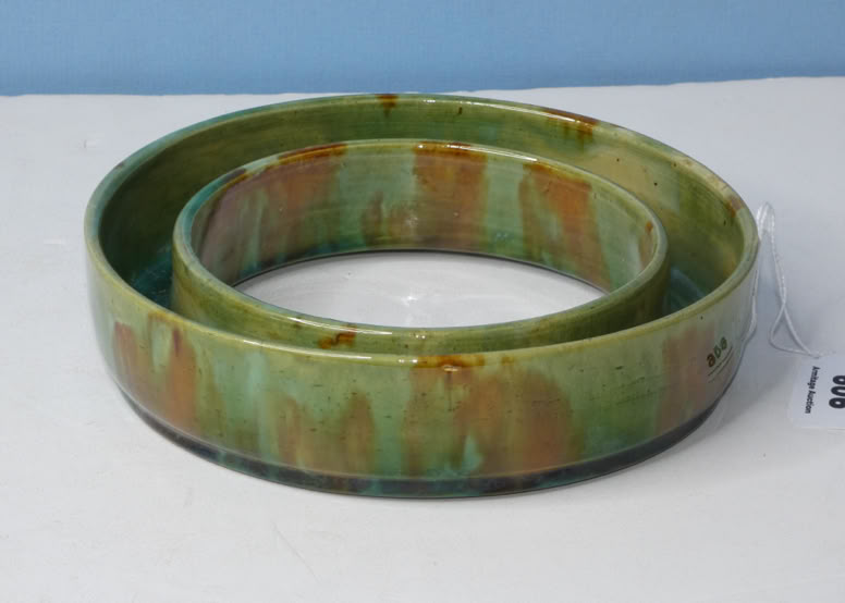 A green and brown ceramic ring-shaped object on a white surface.