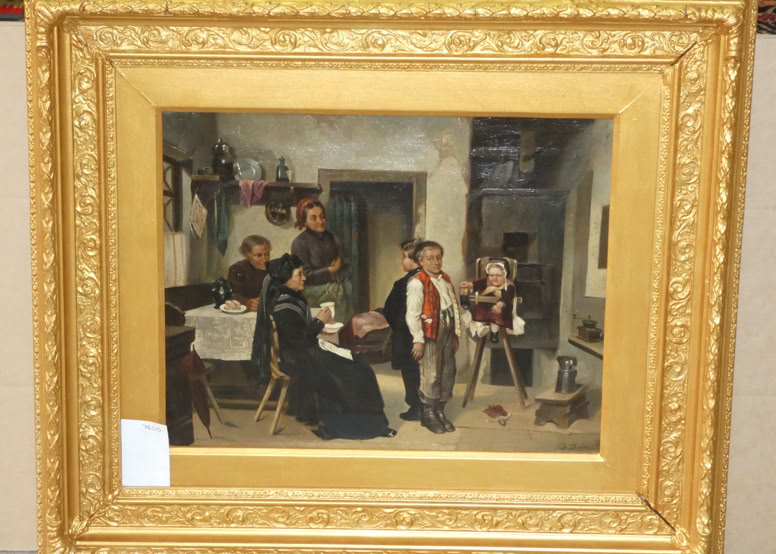 A framed painting depicting a group of people in a room, with some seated and others standing, surrounded by various objects and furniture. The frame is ornate and gold-colored.