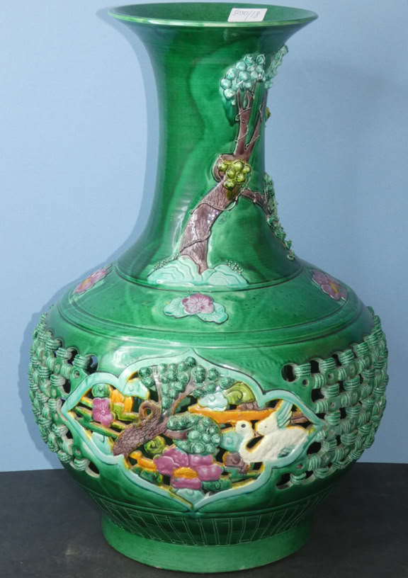 Green decorative vase with intricate cut-out patterns and colorful floral designs.