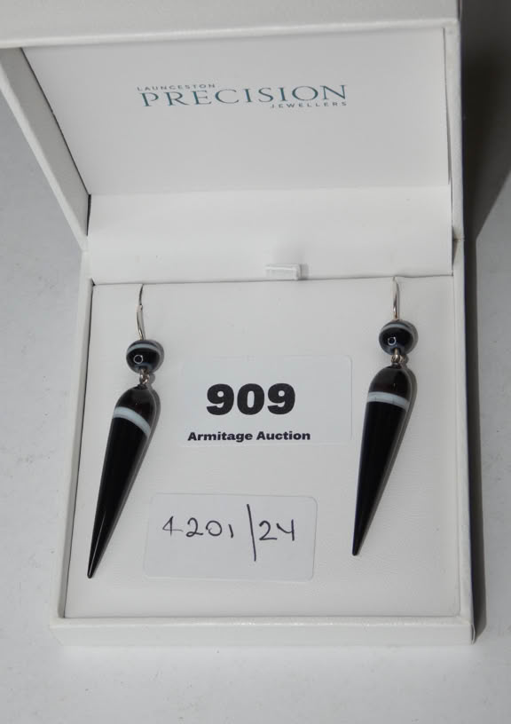A pair of black and white drop earrings in a white box labeled "PRECISION," with a card displaying "909" and "4201/24."