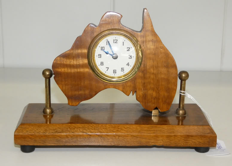 Wooden clock shaped like the map of Australia, mounted on a rectangular wooden base with two vertical supports.