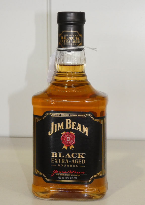 A bottle of Jim Beam Black Extra Aged Bourbon with a black label and gold accents, placed on a light-colored surface.